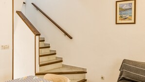 A bedroom with a bed, a wooden staircase, and a framed painting on the wall. - Holiday Home 'Palau 100m Playa' with Private Terrace and Wi-Fi (L'Escala)