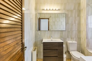 Une salle de bain avec une porte en bois, un lavabo, un miroir et des toilettes.