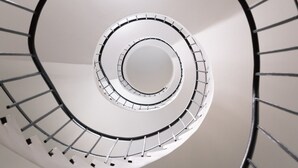 Una scala a chiocciola con colonna centrale e balaustre su entrambi i lati.