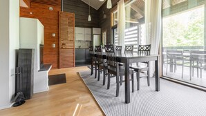 A modern kitchen with wooden accents, a dining area with a large table and chairs, and large windows providing natural light.