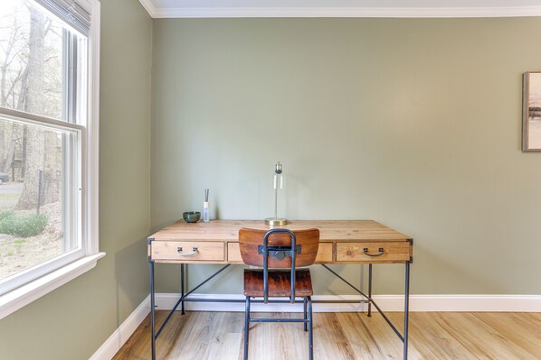 Een kamer met een houten bureau, een stoel, een lamp en een raam.