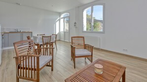 A spacious room with a dining area, a kitchen, and large windows.