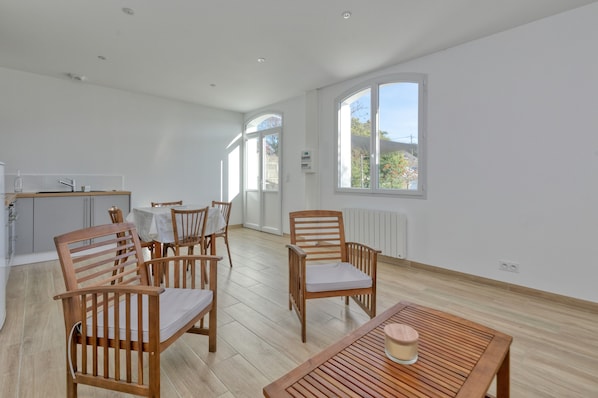 A spacious room with a dining area, a kitchen, and large windows.