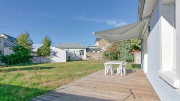 A patio with a table and chairs, a white building, and a clear blue sky.
