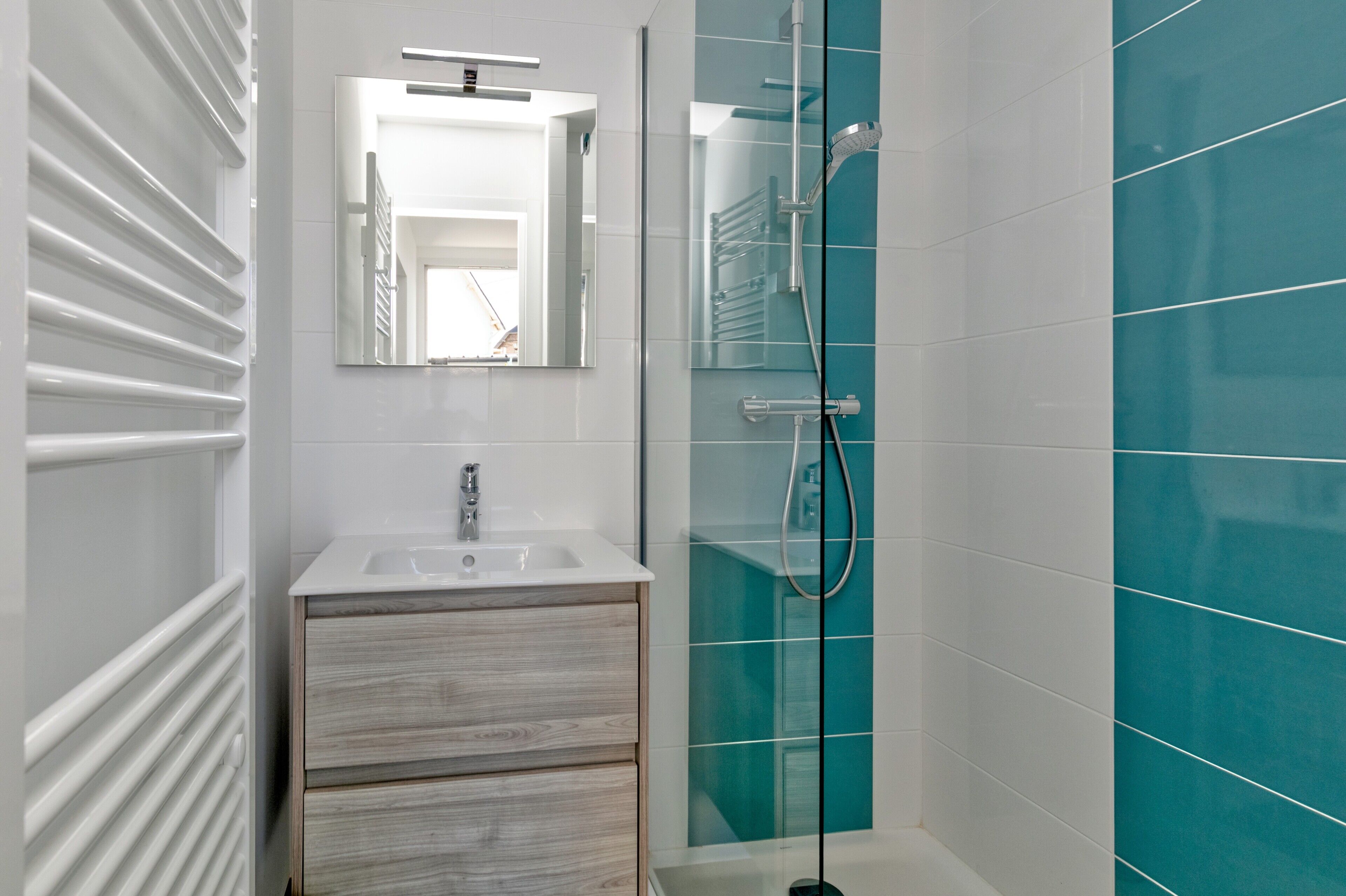 A modern bathroom with a glass shower enclosure, a white sink, and a wooden vanity.