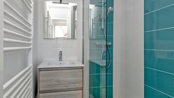A modern bathroom with a glass shower enclosure, a white sink, and a wooden vanity.