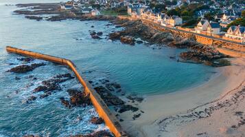 A coastal town with a beach, a sea wall, and houses along the shore.