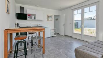 A modern kitchen with a dining area, a sofa, and a sliding glass door leading to an outdoor patio.
