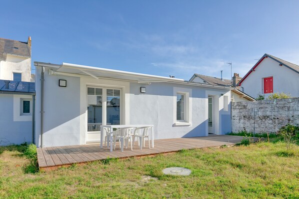Une maison moderne dotée d’un patio, d’une façade blanche et d’une porte rouge.