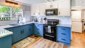 A kitchen with blue cabinets, a black oven, and a white refrigerator. - Walk to River & Trails: Cozy Damascus Cottage! (Damascus)