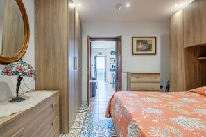 A bedroom with a bed, a dresser, a mirror, and a door leading to another room.