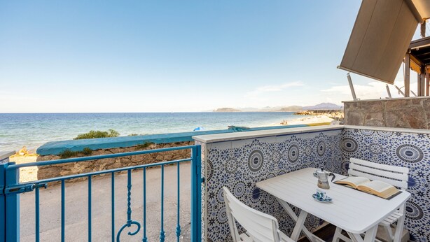 A seaside patio with a table and chairs, a view of the ocean, and a patterned wall.