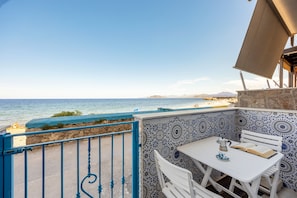 Eine Terrasse am Meer mit Tisch und Stühlen und Blick auf den Ozean, sowie eine Wand mit Muster.