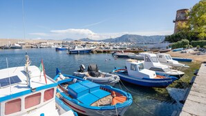 A marina with various boats docked, a clear sky, and a mountainous backdrop.