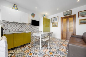 Eine moderne Küche mit gefliestem Rücksprung, ein Essbereich mit Tisch und Stühlen sowie eine Sitzecke mit einer Couch.