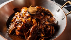 A close-up of a dish with shredded meat and vegetables in a pan. - JYXDYJYJYGJYGJGYJ (Centro Florianópolis)