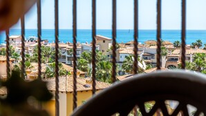 Un balcón con vistas a un pueblo costero, con edificios y palmeras.