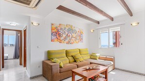 Una sala de estar con un sofá, una mesa de centro y un cuadro abstracto de colores.