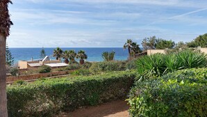 Un paysage côtier offrant une vue sur la mer, avec un mur de pierre et une végétation luxuriante.