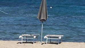 Une plage avec deux chaises longues et un seul parasol.