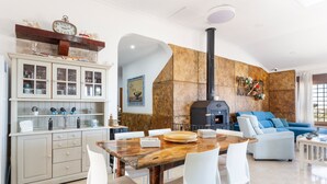 Une cuisine moderne avec un mur en pierre, une table à manger en bois et des chaises blanches.