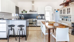 Une cuisine moderne avec des meubles blancs, une table à manger en bois et deux tabourets de bar.