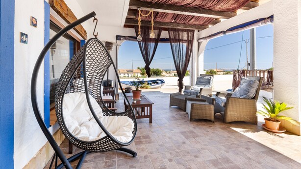 Une terrasse dotée de meubles en osier, d’un fauteuil suspendu et offrant une vue sur la mer.