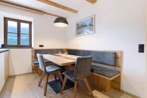 A dining area with a wooden table, grey upholstered bench seating, and a pendant light.