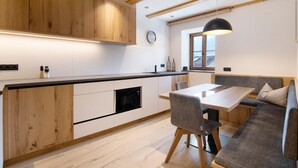 A modern kitchen with wooden cabinets, a dining area with a table and chairs, and a built-in oven.