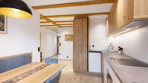 A modern kitchen with wooden beams, a dining area with a bench, and a built-in stove.
