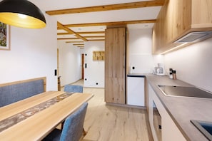 A modern kitchen with wooden beams, a dining area with a bench, and a built-in stove.