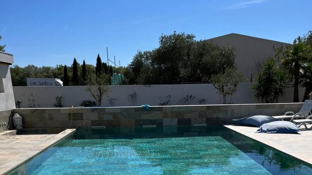 A rectangular swimming pool with clear water, surrounded by a stone deck. - QUIET HOUSE (Cuxac-d'Aude)