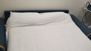A bed with a white textured blanket and a dark headboard. - QUIET HOUSE (Cuxac-d'Aude)