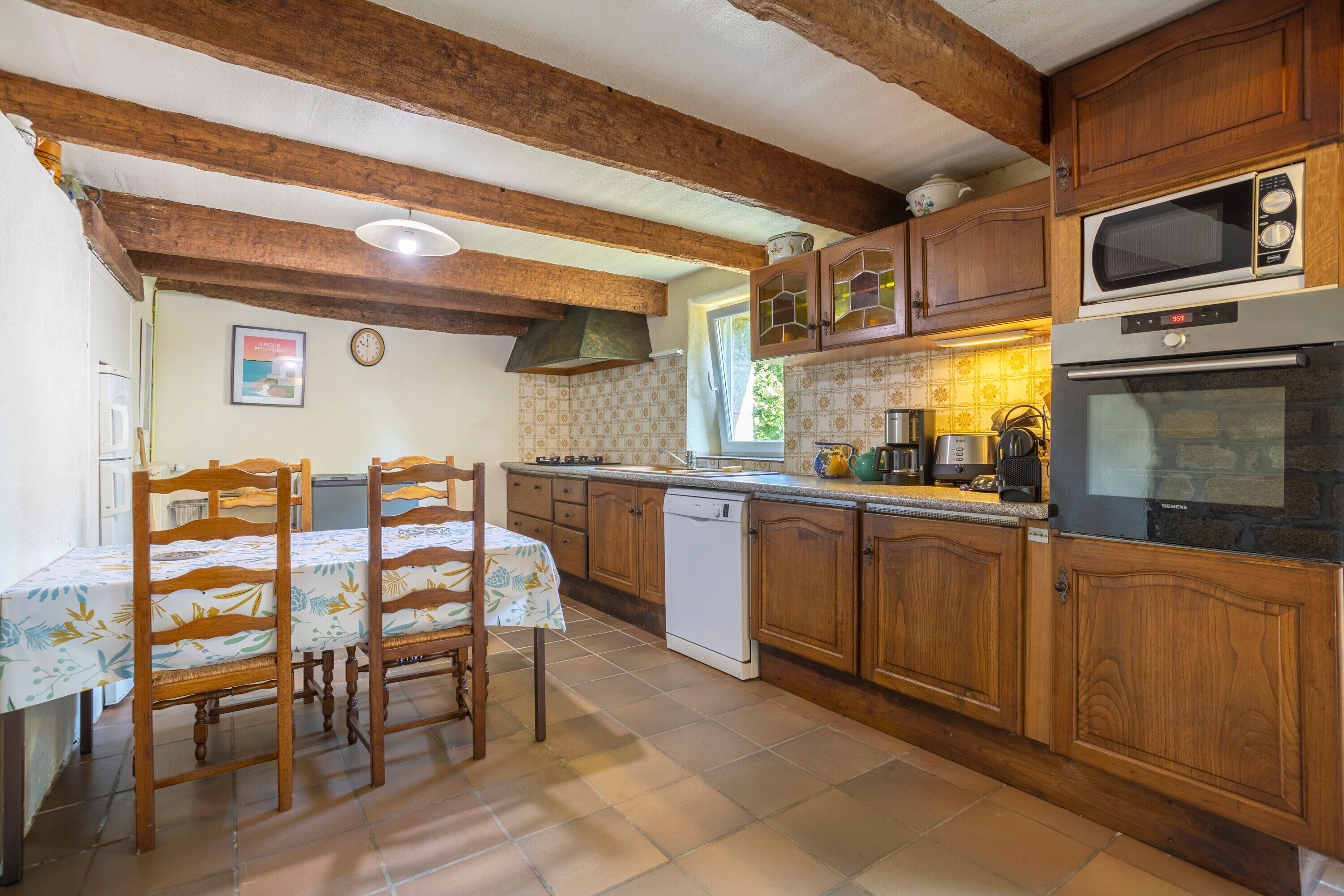 A kitchen with wooden cabinets, a microwave, an oven, a dishwasher, and a dining table with chairs.