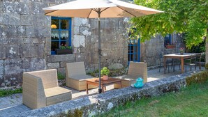 Un espace extérieur aménagé avec des meubles en osier, une table et un grand parasol.