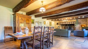 Un coin repas avec une table et des chaises en bois, un canapé et une cheminée en pierre.