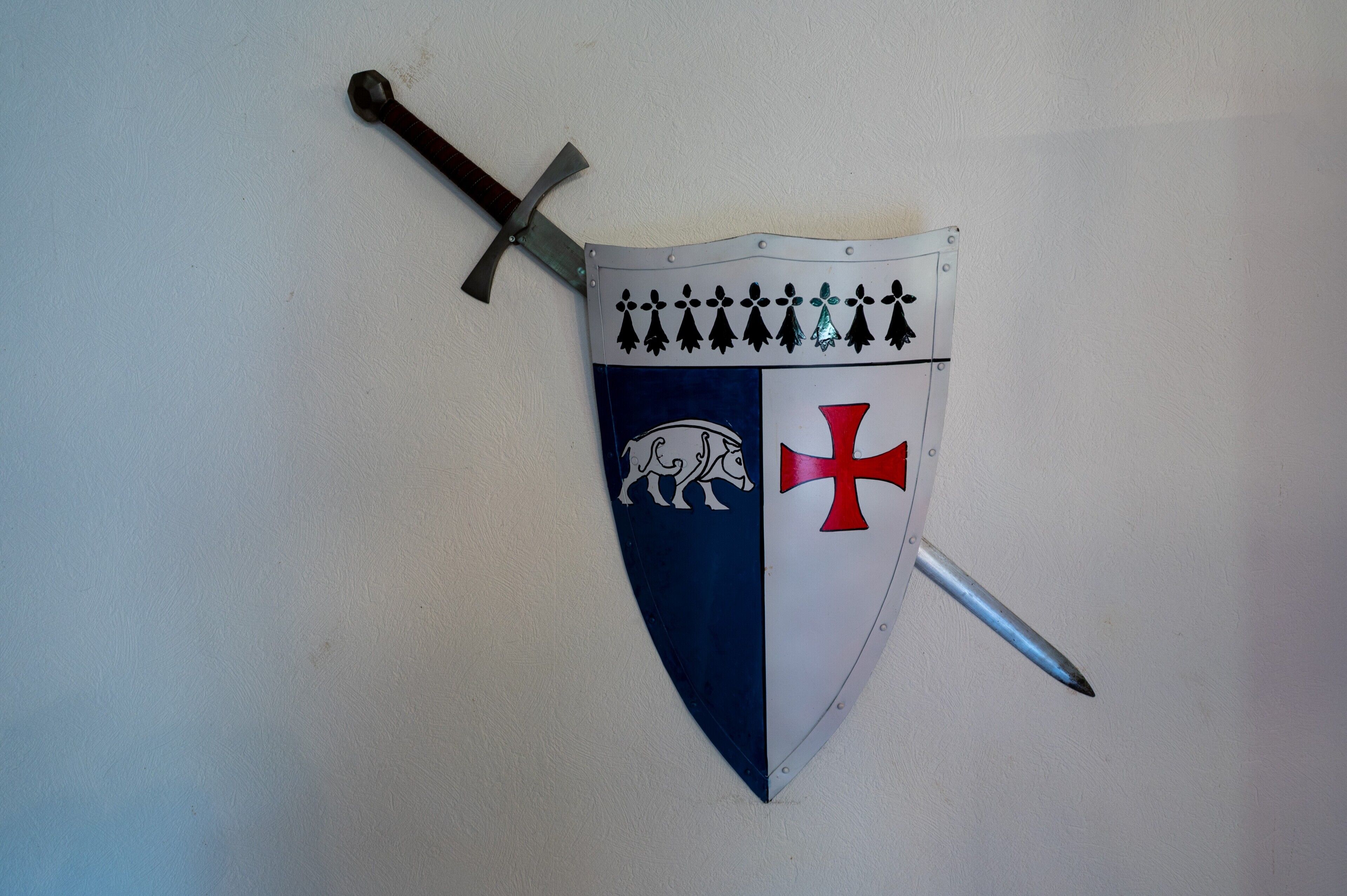 A shield with a sword, featuring a cross and a horse emblem.