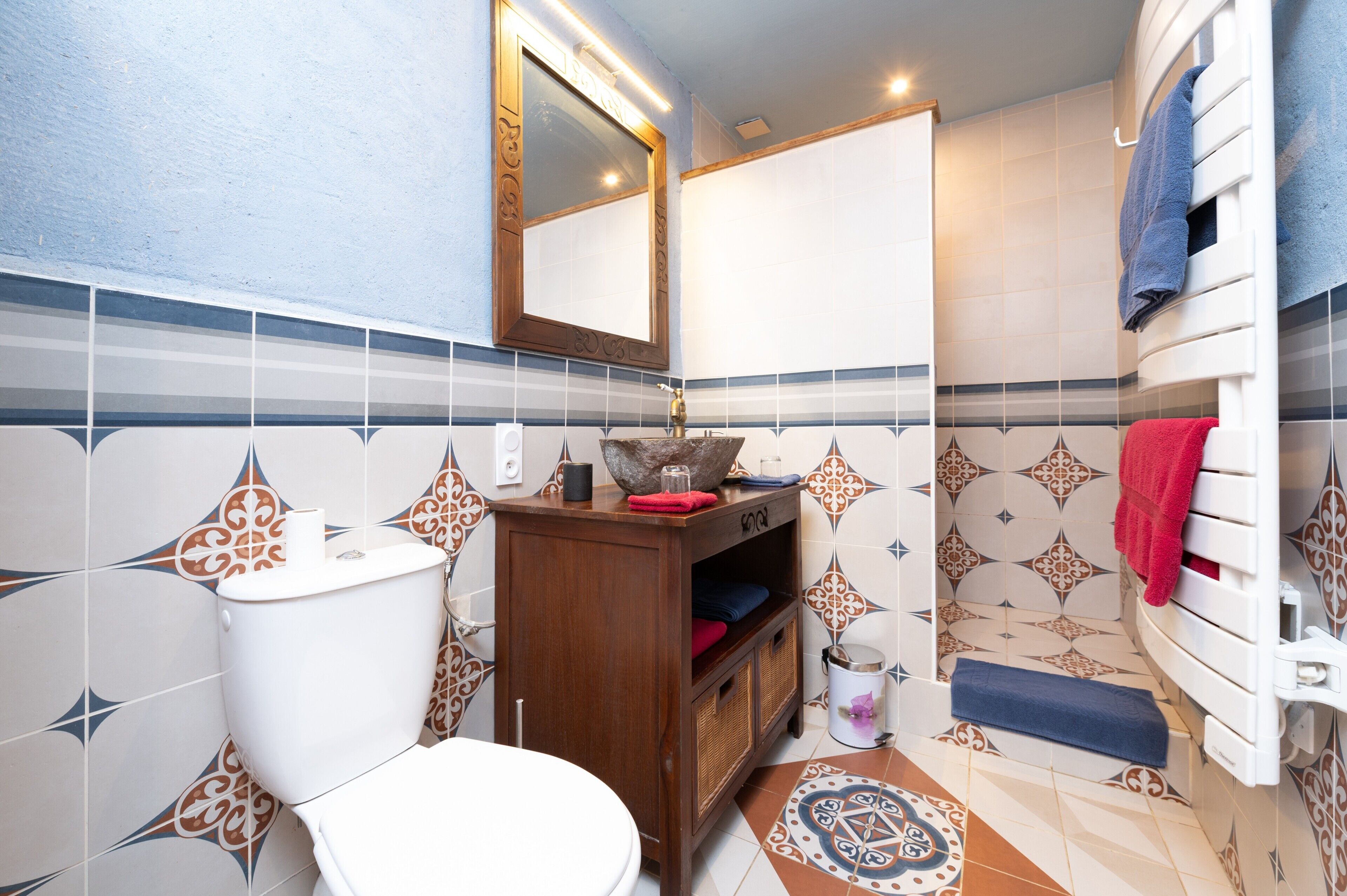 Une salle de bain équipée de toilettes, d’un lavabo, d’un miroir et d’un porte-serviettes.