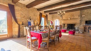 Un comedor con pared de piedra, vigas de madera, chimenea y una mesa preparada para cuatro.