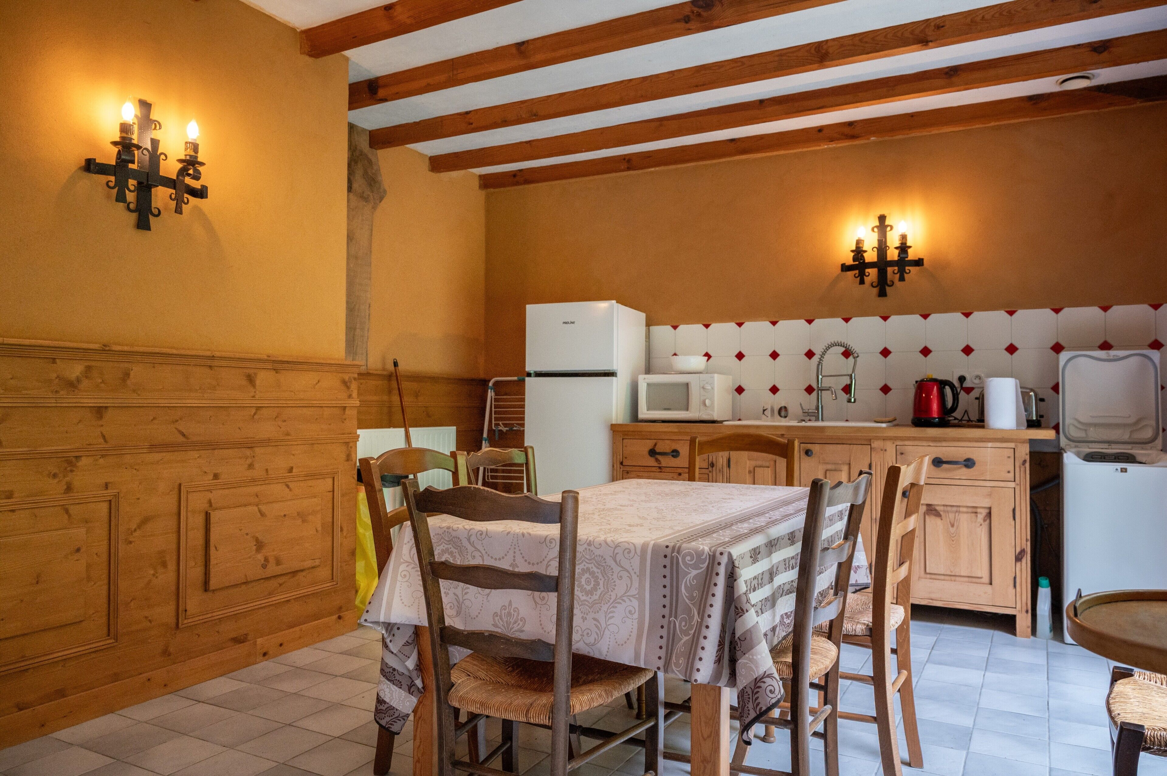 Una cucina con mobili in legno, un frigorifero, un forno a microonde e un tavolo da pranzo con sedie.