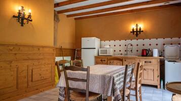 Una cucina con mobili in legno, un frigorifero, un forno a microonde e un tavolo da pranzo con sedie.