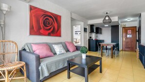 A living room with a sofa, a coffee table, a dining table, and a kitchen area in the background. - Apartment 'Rincon Del Arenal' with Sea View, Wi-Fi and Air Conditioning (Platja de l'Arenal)