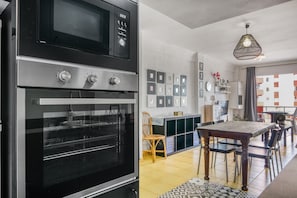 A kitchen with a built-in oven, a dining area with a table and chairs, and a hanging light fixture. - Apartment 'Rincon Del Arenal' with Sea View, Wi-Fi and Air Conditioning (Platja de l'Arenal)