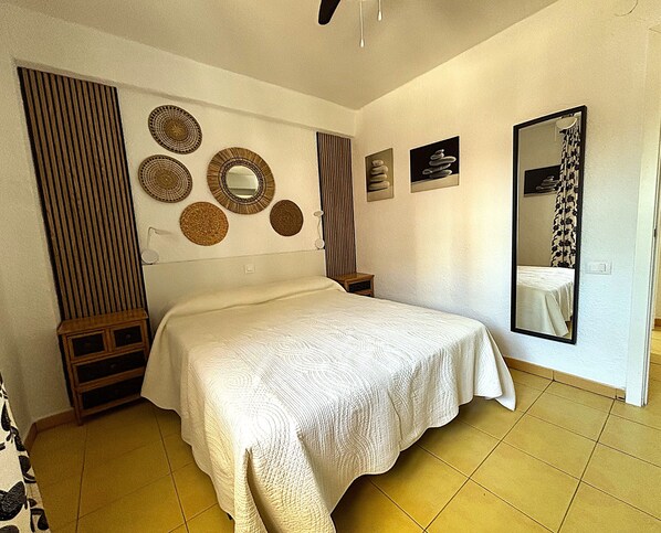 A bedroom with a bed, a mirror, wall decor, and a wooden cabinet.