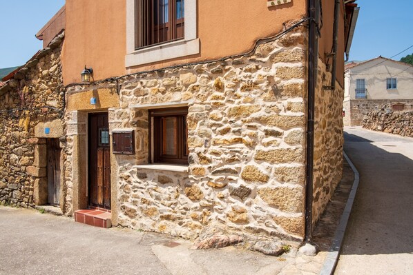 A stone building with a wooden door, a window, and a small porch.
