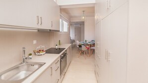 A modern kitchen with a sink, stove, and dining area with chairs and a table. - Apartment 'Mantisses Studio' with Shared Terrace, Wi-Fi and Air Conditioning (?a?aµ?ta)