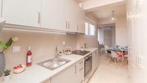 A modern kitchen with a sink, stove, and dining area with chairs and a table. - Apartment 'Mantisses Studio' with Shared Terrace, Wi-Fi and Air Conditioning (?a?aµ?ta)