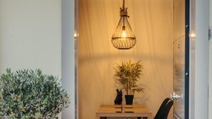 A dining area with a table, chairs, a hanging light fixture, and a potted plant.