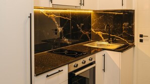 A modern kitchen with white cabinets, black countertops, a black stove, and a sink.