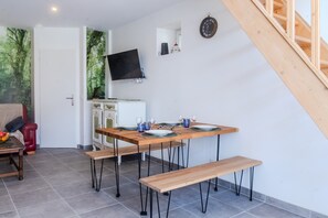 A dining area with a wooden table, benches, and a TV mounted on the wall.